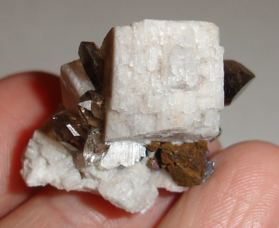 Smoky quartz, microcline, hematite pseudomorph, and limonite pseudomorph on matrix