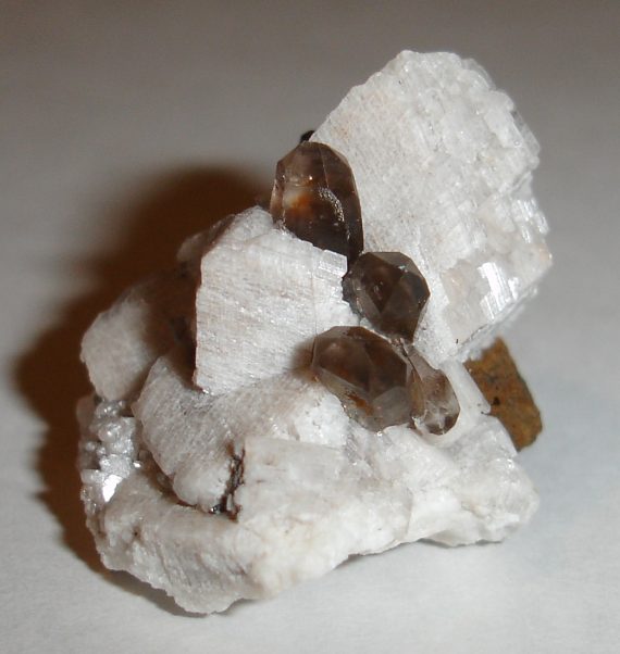 Smoky quartz, microcline, hematite pseudomorph, and limonite pseudomorph on matrix