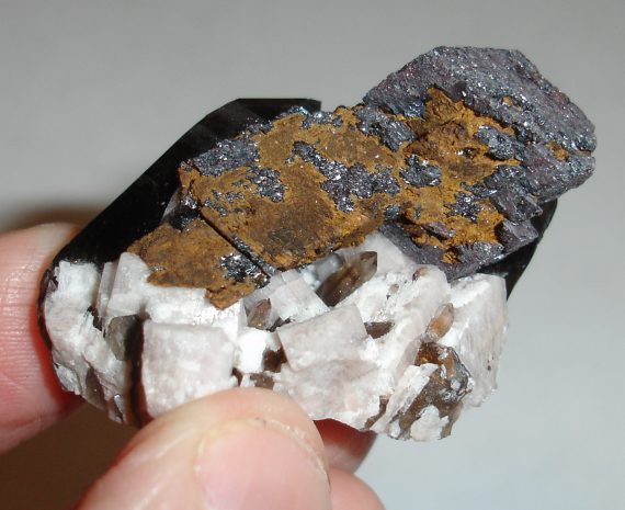 Hematite pseudomorph, smoky quartz, microcline, and albite