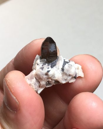 Smoky quartz crystals on a matrix of microcline and albite, with specular hematite
