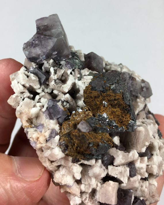 Fluorite, hematite pseudomorph after siderite, microcline, and albite on matrix