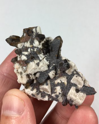 Smoky quartz, microcline, and albite with a coating of specular hematite