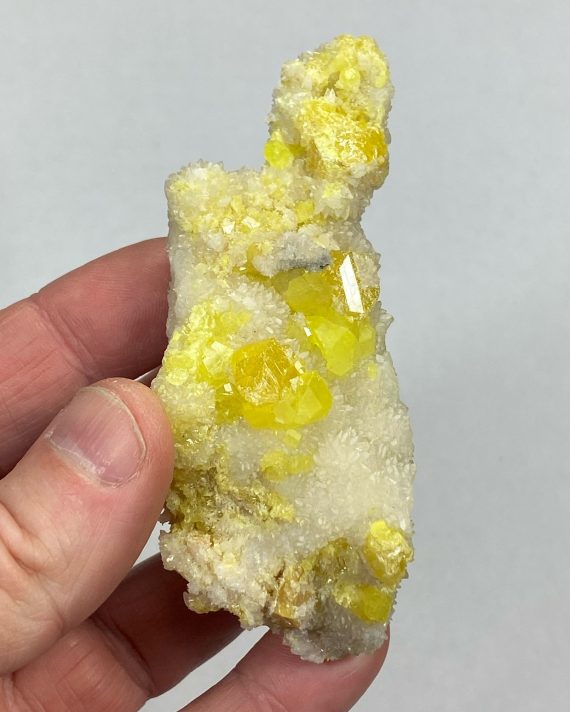 Bright yellow Sulfur crystals on a bed or Aragonite (which is fluorescent)