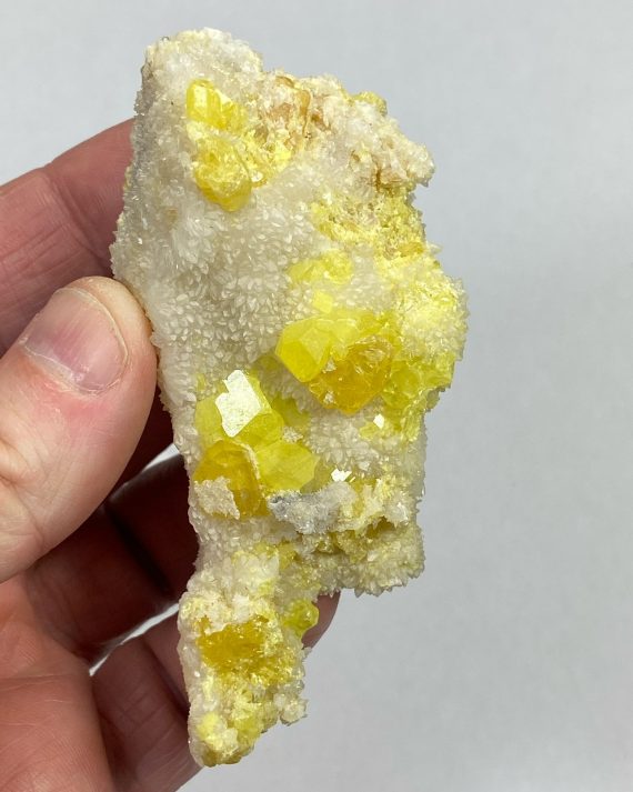 Bright yellow Sulfur crystals on a bed or Aragonite (which is fluorescent)
